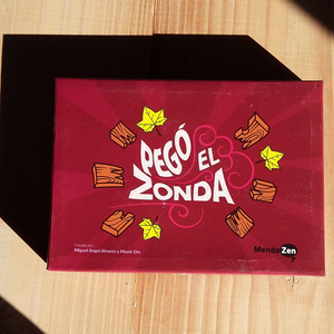 Caja del Juego. Tapa Roja con ilustración de maderas rotas y hojas de árbol. Título Pegó el Zonda. Editorial MendoZen